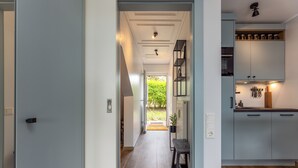 A modern kitchen with grey cabinets, a wooden countertop, and a built-in shelf with jars. - Isola - Wenningstedt-Braderup (Sylt) (Wenningstedt-Braderup (Sylt))