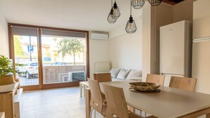 A modern dining area with a wooden table, chairs, and a basket. There is a white refrigerator and a sofa in the background. - Ca' Linda By Case al Lago (Desenzano del Garda)
