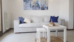 A modern living room with a white sofa, a coffee table, and abstract art on the wall. - Ca' Linda By Case al Lago (Desenzano del Garda)