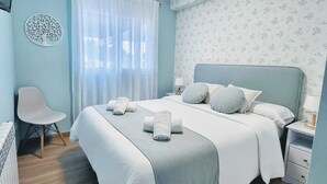 Ein ordentlich eingerichtetes Schlafzimmer mit einem Bett, einem Sessel, einem Nachttisch und einer Wanddekoration.