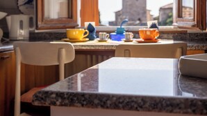 A kitchen with a granite countertop, a window with a view of a tower, and various kitchen items like a kettle and cups.