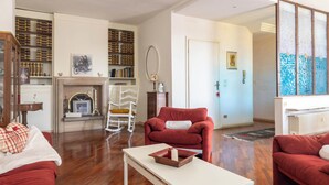 A living room with a fireplace, red sofas, a white coffee table, and a bookshelf.