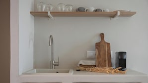 Cuina amb un rentaplat de color blanc, una taula de tall de fusta, una tetera i una tovallola petita al taulell.