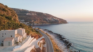 Una carretera costanera amb edificis damunt d'una collada, amb vista al mar.