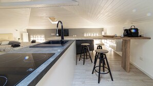A modern kitchen with a central island, bar stools, and a built-in stove.
