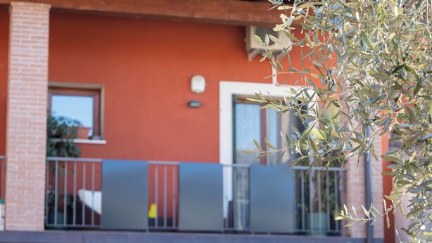 A building with a red facade, a balcony with metal railings, and a window. - Maison 140 By Case al Lago (Lonato)