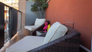 A wicker sofa with white cushions on a balcony with a brick wall and a plant. - Maison 140 By Case al Lago (Lonato)