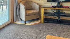 A cozy cabin interior with a wooden ceiling, a television, a sofa, and a dining area. - Ahmic Lake Resort's Black Bear Cottage (Magnetawan)