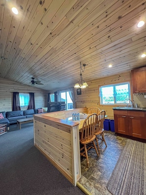 A cabin interior with a dining area, kitchen, and living room.
