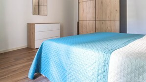 Un dormitorio con una cama, un armario de madera y un espejo en la pared.
