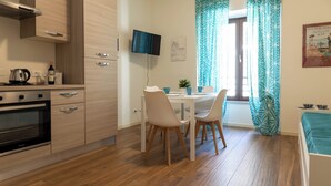 Una cocina moderna con armarios de madera, horno empotrado y comedor con mesa y sillas.