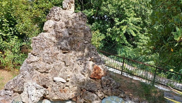 Un bassin rocheux agrémenté de nénuphars et surmonté d’une structure en pierre.