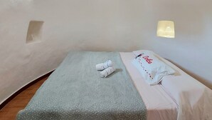 Une petite chambre à coucher, chaleureuse et accueillante, avec un lit simple, une fenêtre et un luminaire fixé au mur.