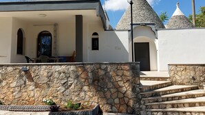 Un bâtiment doté d’une façade en pierre, d’un porche carrelé et d’un escalier menant à une porte.