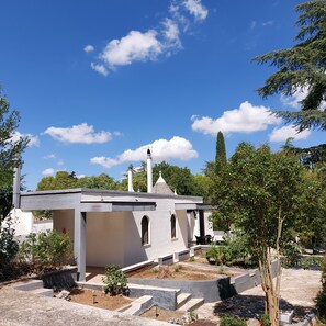 A small, white building with a flat roof and a chimney, surrounded by trees and a clear blue sky. - Puglia Tu (Putignano) By Case al Lago (Putignano)