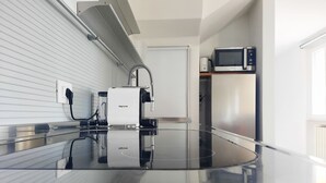 Una cocina moderna con una encimera brillante, microondas integrado y cafetera.