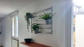 Un pasillo con un estante de madera, un radiador y un mueble de pared para plantas con tres ejemplares.