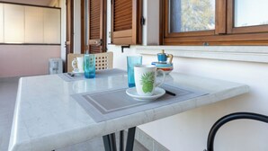 A kitchen area with a marble countertop, a coffee maker, and a window with wooden shutters.