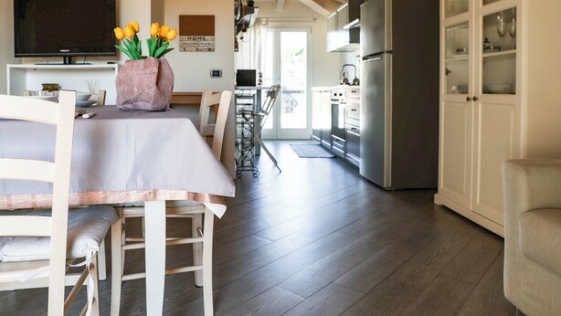 A modern kitchen with a built-in oven and refrigerator, a dining area with a table and chairs, and a TV on the wall. - Casa Monia By Case al Lago (Lonato)