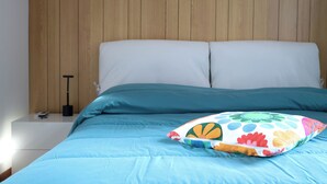 Un lit avec une couvre-lit bleue et deux oreillers, dont l’un est orné d’un motif floral multicolore.