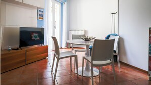 Un salon avec un téléviseur, une table à manger et des chaises.