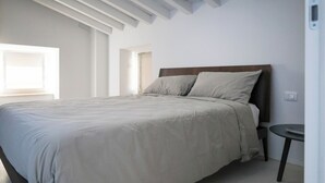 A bedroom with a large bed, a small round table, and a window providing natural light. - Vicolo dei Signori By Case al Lago (Desenzano del Garda)