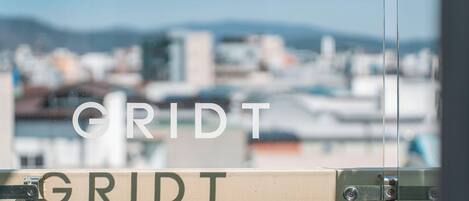 A sign with the word "GRIDT" on a metal structure, with a blurred cityscape in the background.