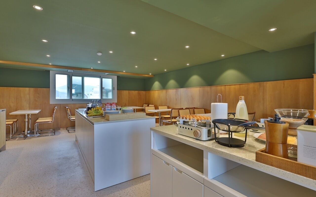A modern kitchen with a central island, bar stools, and a window overlooking a scenic view.