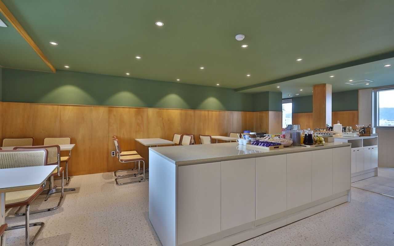 A modern kitchen with a central island, wooden paneling on the walls, and a seating area with tables and chairs.