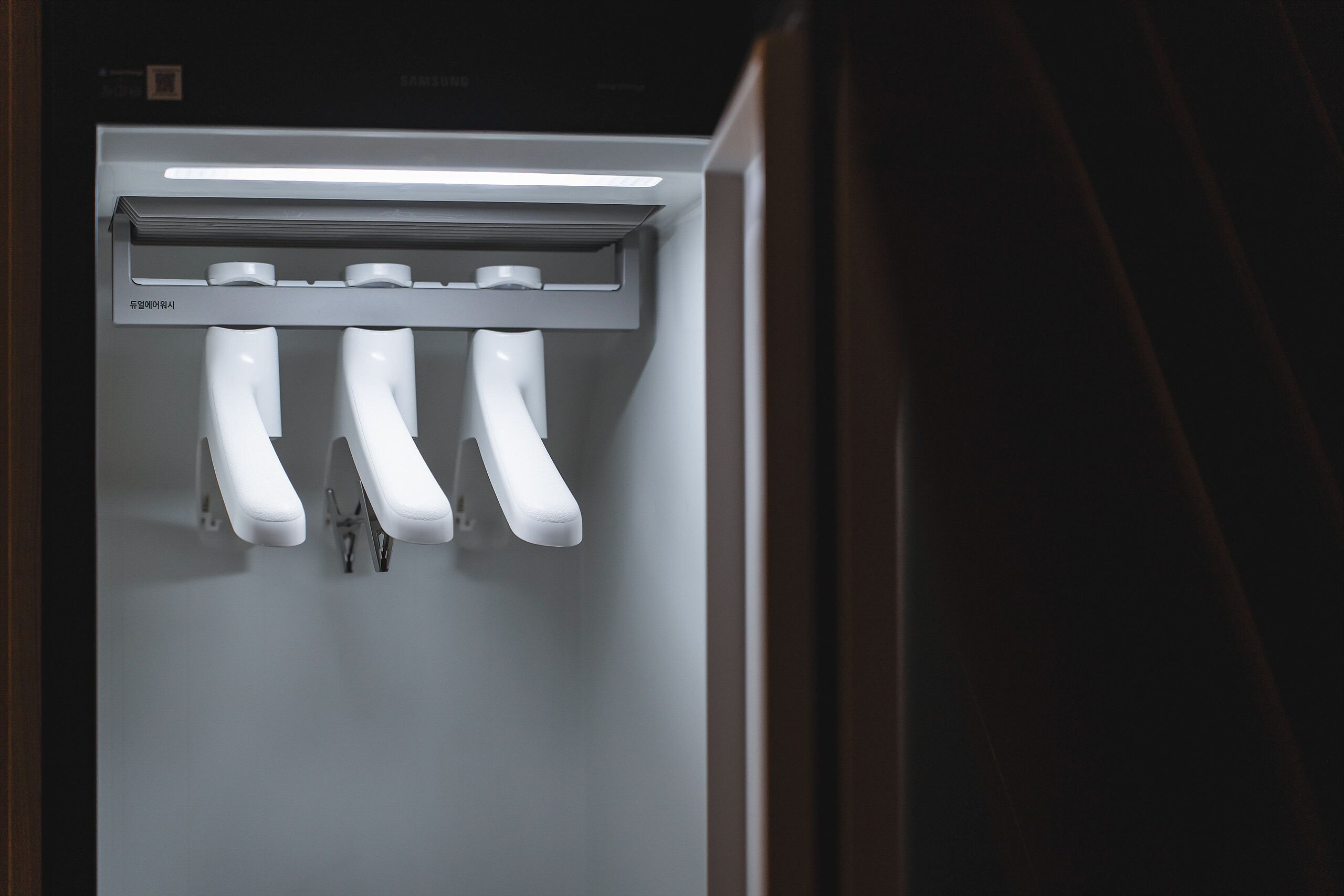 Un baño moderno y bien iluminado con un diseño elegante, que incluye un lavamanos de pared y un secamanos.