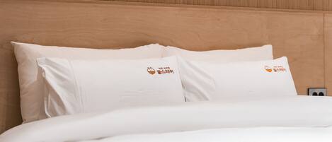 A bed with white bedding and pillows featuring a logo.