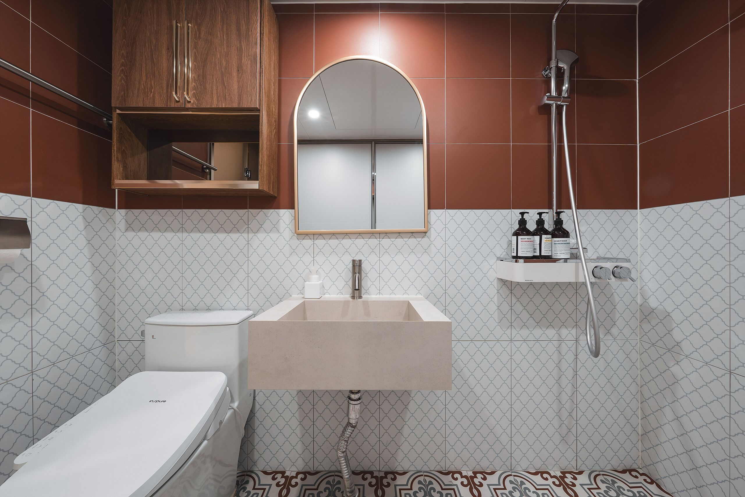 A modern bathroom with a toilet, sink, mirror, and shower.
