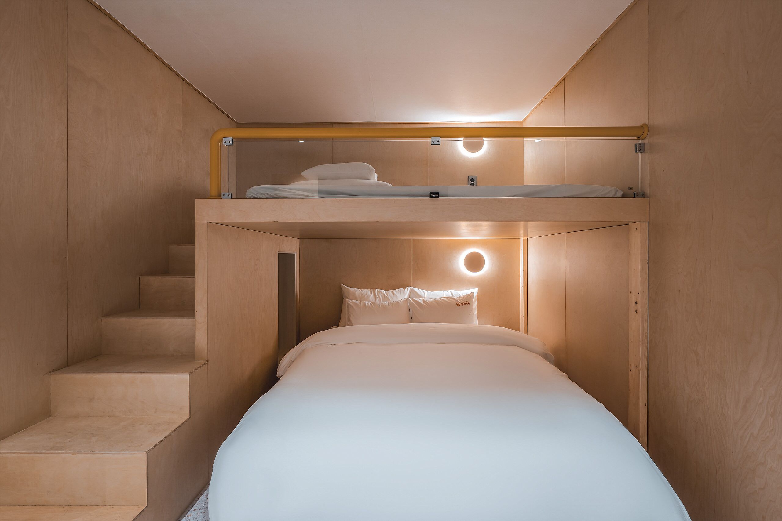 A bunk bed with a headboard and a staircase leading to an upper bunk.
