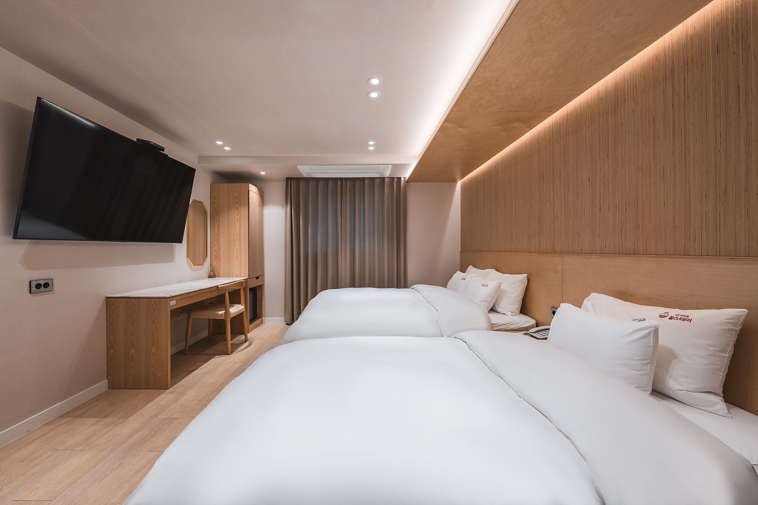 A modern hotel room with a large bed, a desk, a flat-screen TV, and a large mirror.