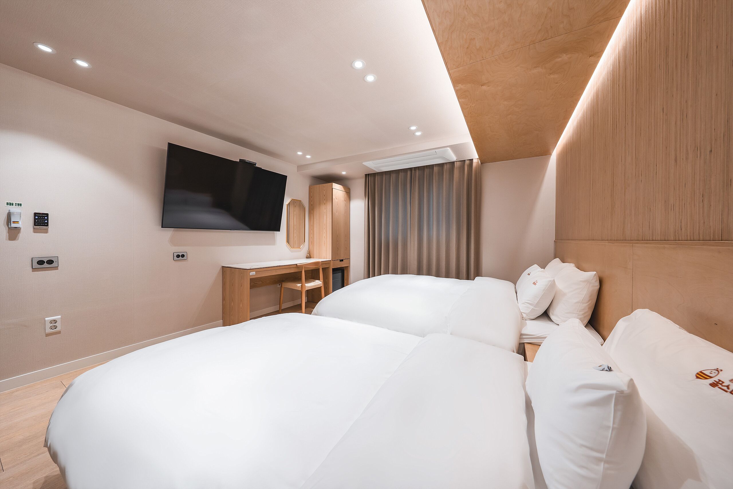 Une chambre d’hôtel moderne, dotée d’un grand lit, d’un bureau et d’un téléviseur à écran plat fixé au mur.