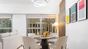 A modern dining area with a round table, two chairs, and a glass partition.