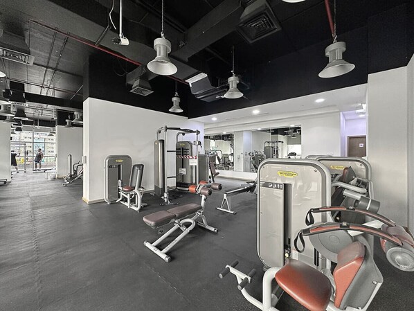 A gym with various exercise machines, a bench, and a mirrored wall.