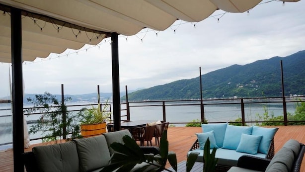 A covered outdoor seating area with a view of a body of water and mountains. - Hotel Himalaya Sea (Ito)