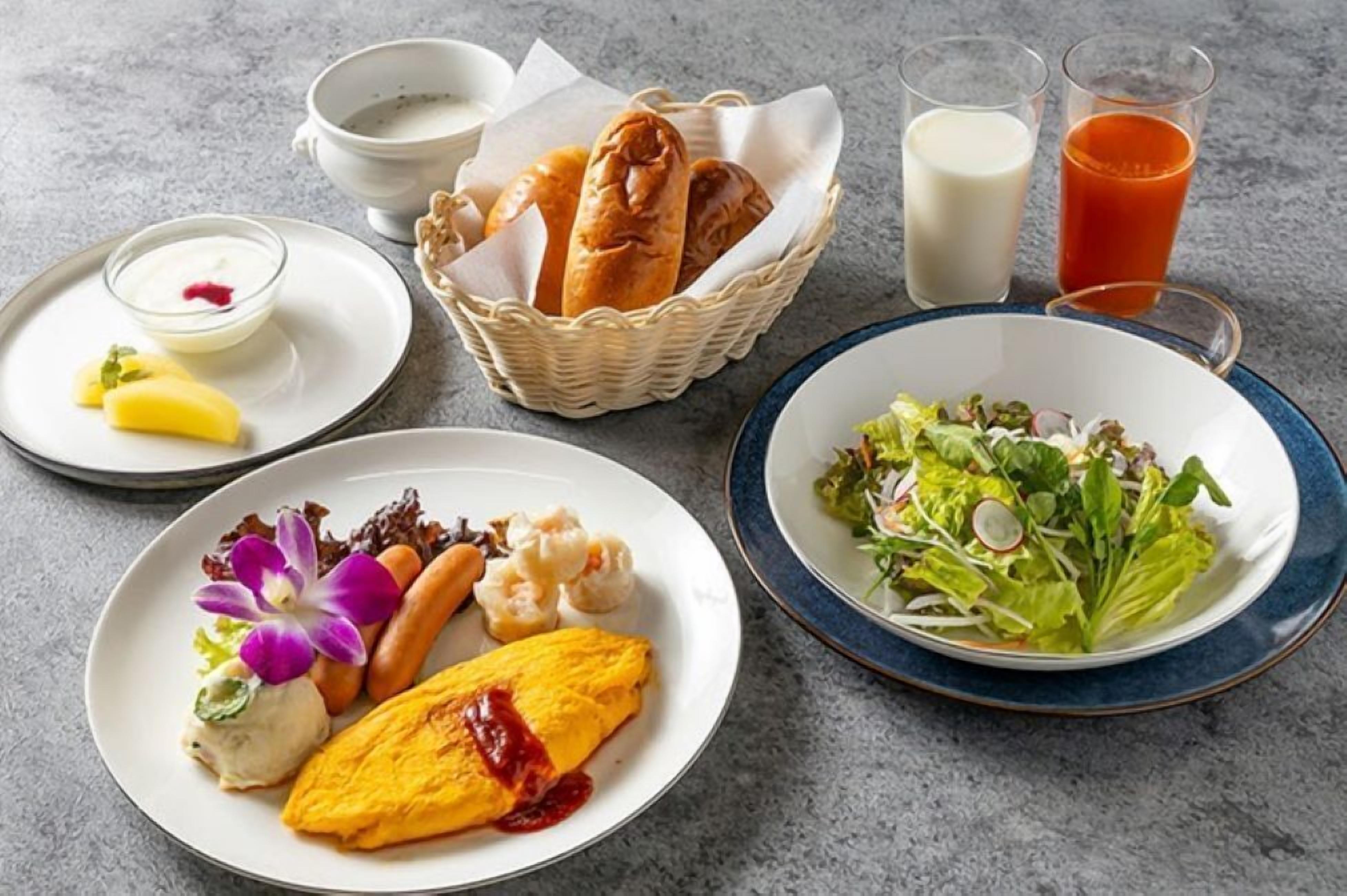Une table dressée avec différents plats, notamment une salade, une assiette d’œufs et de légumes, un bol de soupe et un panier de pain.