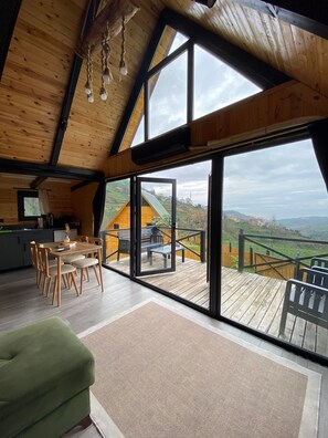 Ein großzügiges Loft mit hoher Decke, großen Fenstern, einem Holzbalkon und einem Essbereich.