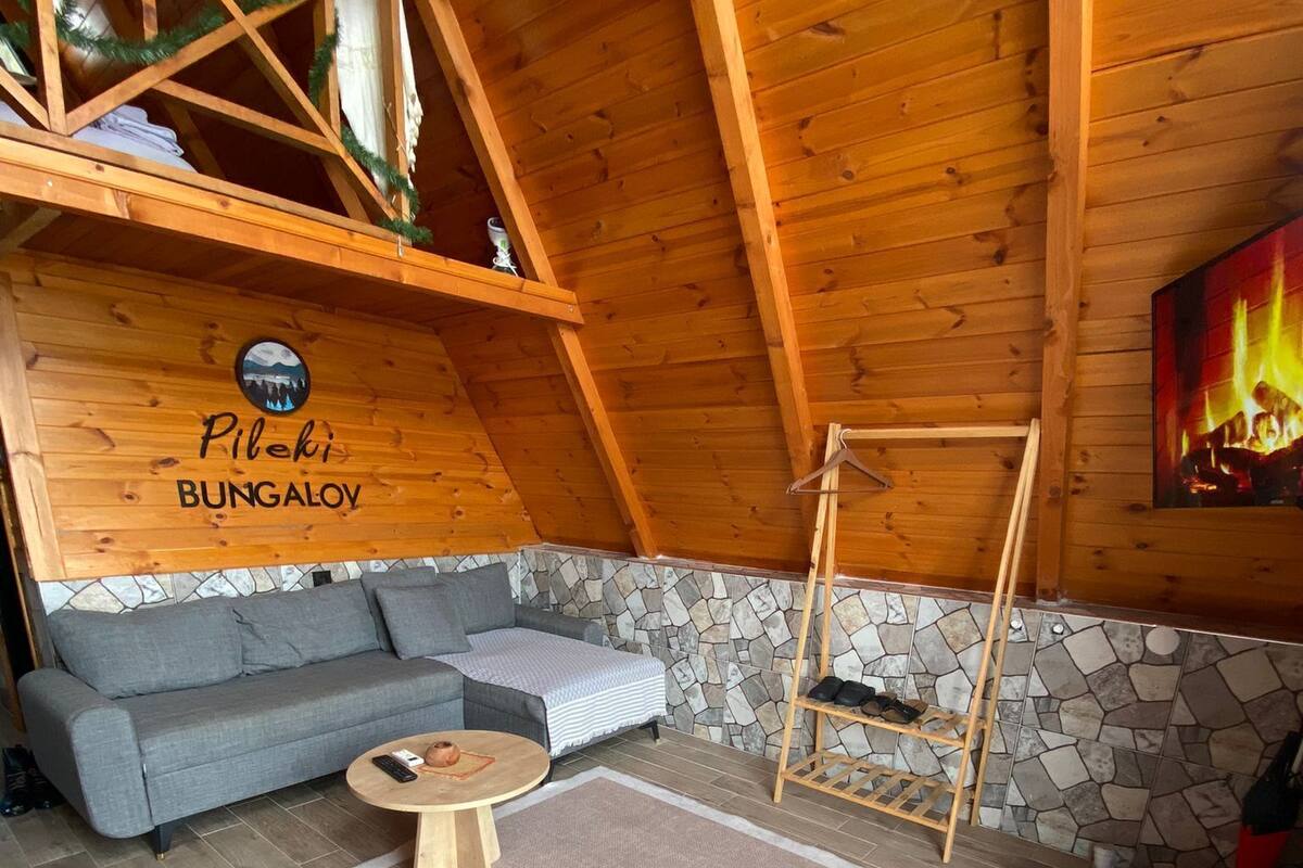 Une pièce chaleureuse avec un mur en pierre, un canapé gris, une table en bois et une cheminée.