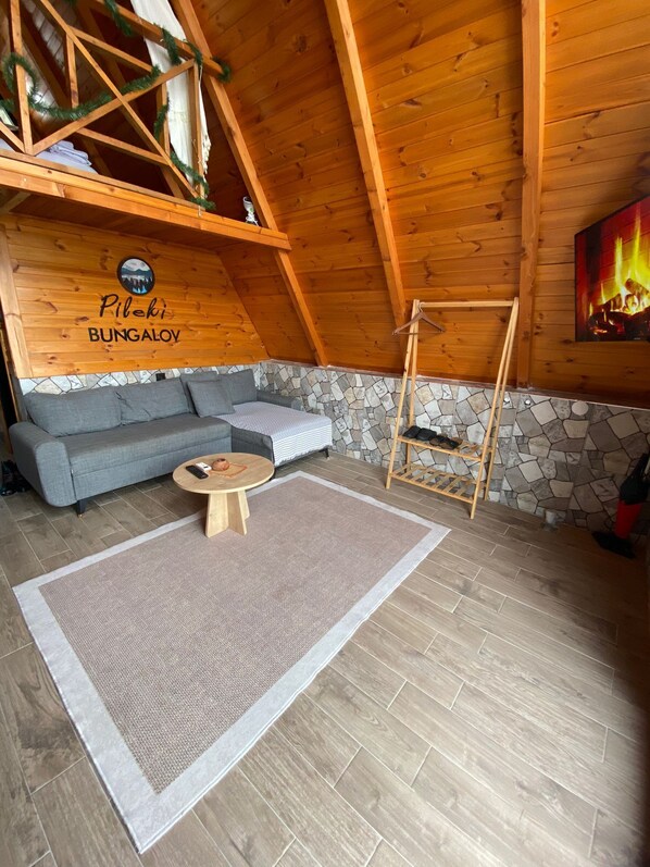 Una habitación acogedora con pared de piedra, un sofá gris, una mesa de madera y una chimenea.