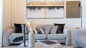 Un salon moderne avec un canapé gris, une table basse en marbre et un tableau accroché au mur.