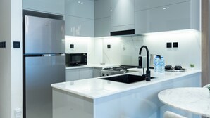 Une cuisine moderne équipée d’un réfrigérateur en acier inoxydable, d’un four à micro-ondes, d’une cuisinière à gaz et d’un évier.