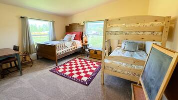 A room with two bunk beds, a small table, a chair, a lamp, and a chalkboard.