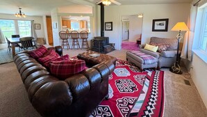 Un salon comprenant un canapé en cuir, un tapis à motifs, un divan et un coin repas avec des chaises et une table.