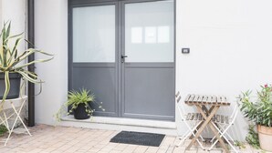 A modern entrance with a grey door, potted plants, and a small wooden table.