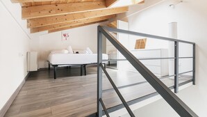 A modern loft bedroom with a sloped ceiling, a bed, and a staircase.