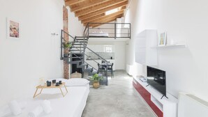 A modern living space with a loft bedroom, a dining area, and a kitchen.