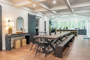 Una cocina moderna con una isla grande, suelo de madera y un comedor con una mesa larga y sillas.
